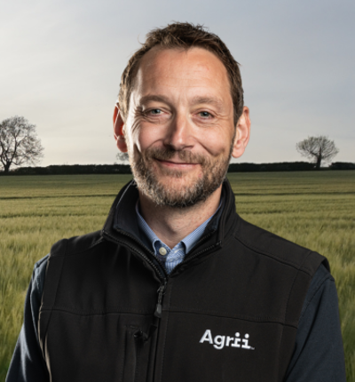 Agrii employee smiling at camera in a wheat field